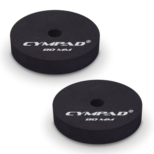 Two black Cympad Moderator cymbal washers, each 80mm in diameter, with a central hole and white printed branding that reads 'CYMPAD 80 MM.' The pads are round, made of cellular foam, and designed to reduce cymbal sustain and volume