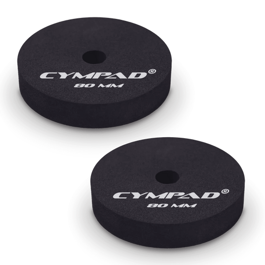 Two black Cympad Moderator cymbal washers, each 80mm in diameter, with a central hole and white printed branding that reads 'CYMPAD 80 MM.' The pads are round, made of cellular foam, and designed to reduce cymbal sustain and volume