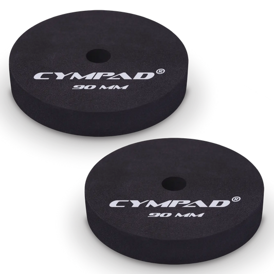 Two black Cympad Moderator cymbal washers, each 90mm in diameter, with a central hole and white printed branding that reads 'CYMPAD 90 MM.' The pads are round, made of cellular foam, and designed to reduce cymbal sustain and volume.